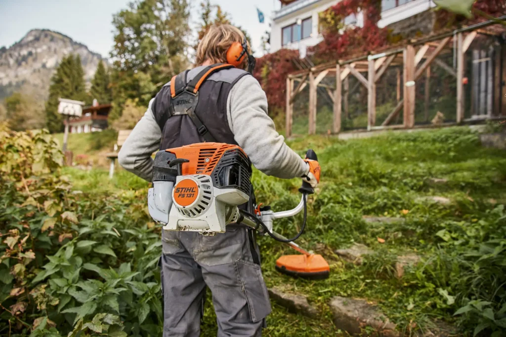 „Angajat STIHL folosind un motoutilaj în aer liber, într-un peisaj montan – simbol al utilajelor performante produse de companie.