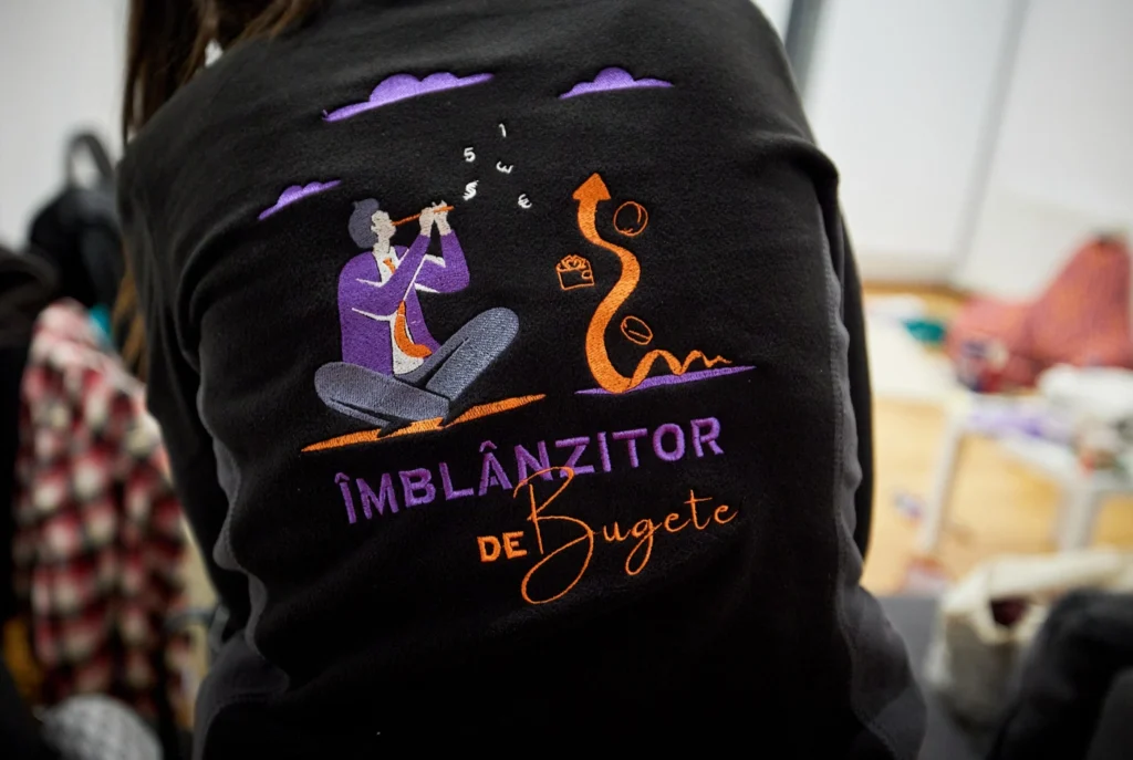 Joc de cuvinte creat de Andra Calenic din echipa Banometru. Fotografie de la întâlnirea de Crăciun de final de an 2024, când toata echipa AEVR a primit cadou hanorace cu Îmblânzitorul.